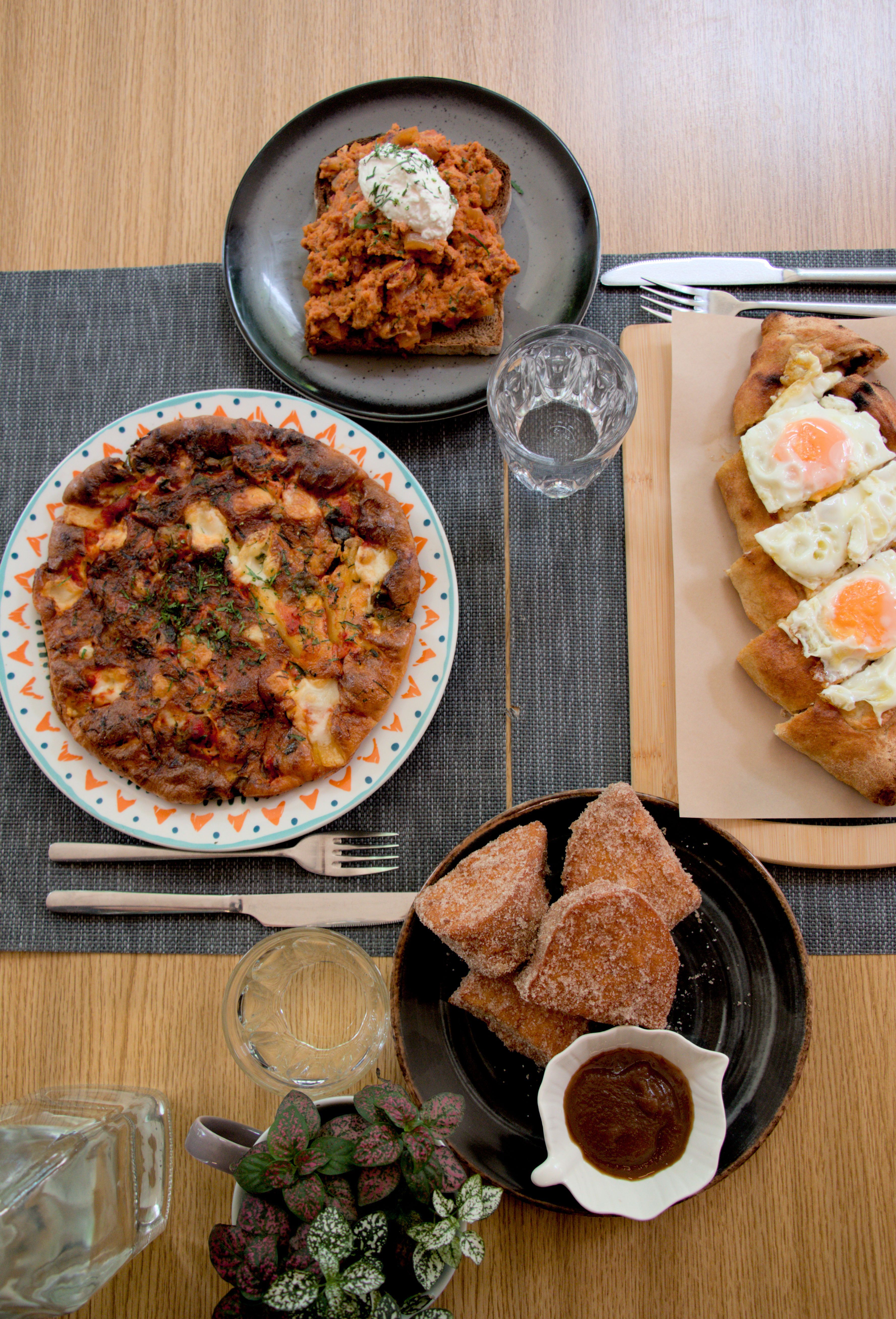 Top down view of a table set for 2 people sitting across each other. There are 4 plates with food, that look quite tasty